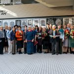 Parodos „Simetrinis karpinio identiteto kodas“ dalyviai ir organizatoriai pozuoja bendrai nuotraukai SMK galerijoje „HeyArt“, popieriaus karpinių ekspozicijos fone.